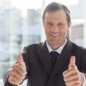 Smiling businessman giving thumbs up in an office